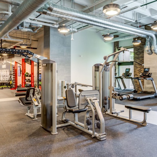 Well-lit fitness center featuring both muscle and cardio equipment State-of-the-art fitness center with strength training machines, cardio equipment, and functional training space at Hermann Park Lofts.